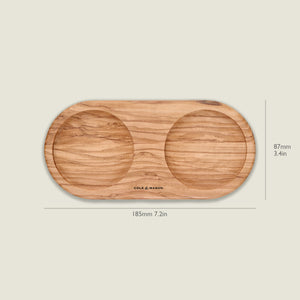 The Cole & Mason Portobello Olive Wood Mill Tray features an oval shape with two circular indentations, ideal for holding salt and pepper mills. It measures 185mm x 87mm and is shown against a plain background.