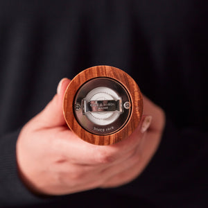 #salt&pepperset A person holds a Cole & Mason Portobello Olive Wood Salt & Pepper Mill, showing its precision grinding mechanism against a dark background.