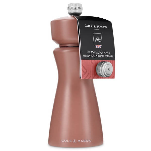 A Cole & Mason Kenton Salt & Pepper Mill in Cinnamon features a rose-colored body with a silver top, labeled for use with either salt or pepper. Showcasing a modern design and equipped with a durable ceramic grinder, the mill includes a tag near the top displaying the Cole & Mason branding and usage instructions.