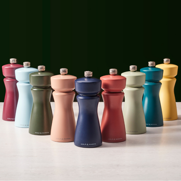 Ten Cole & Mason Kenton Salt & Pepper Mills in Persian Blue Salt are arranged in rows on a light surface against a dark background. Each mill showcases a modern, sleek design with a silver knob on top and features a high-quality ceramic grinding mechanism for durability. These grinders also include adjustable grind settings, letting you customize your seasoning exactly to your preference.