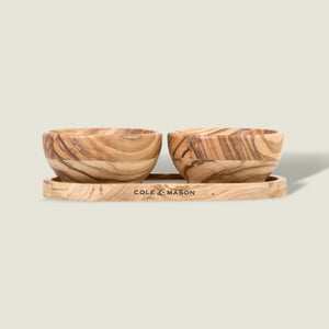 The Cole & Mason Portobello Olive Wood Pinch Pot Set features two small pots with unique grain patterns on a matching tray engraved with the brand name. The set is displayed against a plain, light beige background.