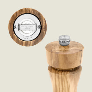 #salt The Cole & Mason Portobello Olive Wood Pepper Grinder stands upright, showing its metal grinding mechanism and grind knob engraved with "Cole & Mason Since 1919"—part of the Portobello Olive Wood Salt & Pepper Mills collection.