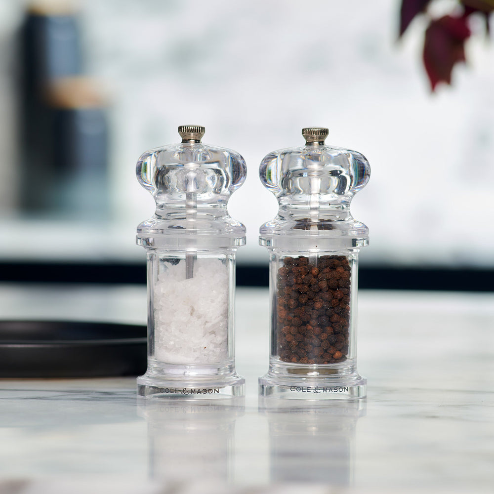 #salt&pepperset
The Cole & Mason 505 Salt & Pepper Mills, crafted from clear acrylic, sit side by side—one with white salt crystals, the other with whole black peppercorns—and feature adjustable settings.