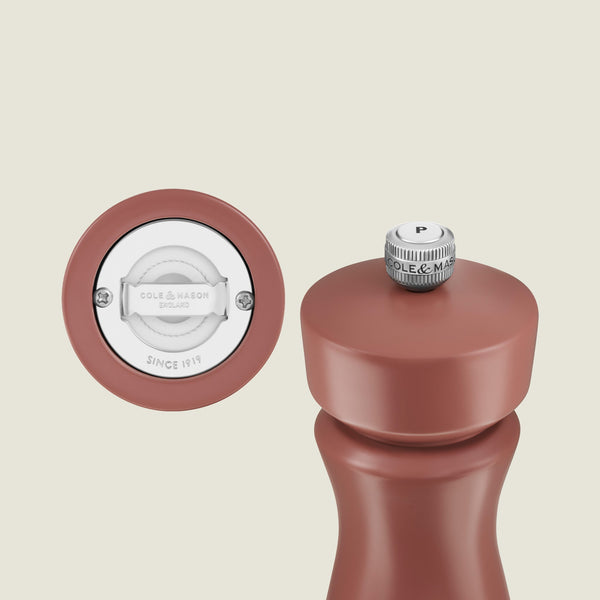 A close-up of the Cole & Mason Kenton Salt & Pepper Mill in Cinnamon features a metal knob labeled “P” on top. The base is shown separately, revealing a white ceramic grinder mechanism engraved with “COLE & MASON ENGLAND”—an elegant addition to your kitchen accessories collection.