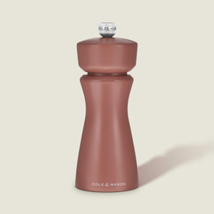 A matte, cinnamon-colored salt and pepper mill with a rounded top and curved body, featuring COLE & MASON in white text at the base, set against a plain, light background. The Kenton Salt & Pepper Mill by Cole & Mason is a stylish kitchen accessory equipped with a durable ceramic grinder for efficient seasoning.