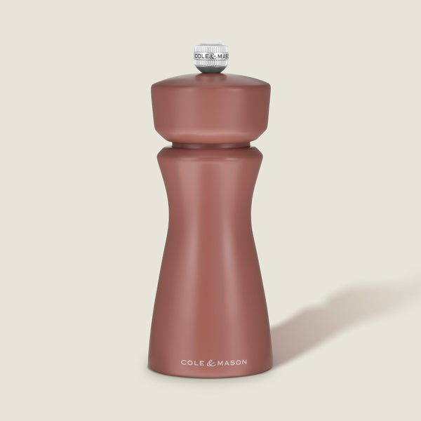 A matte, cinnamon-colored salt and pepper mill with a rounded top and curved body, featuring COLE & MASON in white text at the base, set against a plain, light background. The Kenton Salt & Pepper Mill by Cole & Mason is a stylish kitchen accessory equipped with a durable ceramic grinder for efficient seasoning.