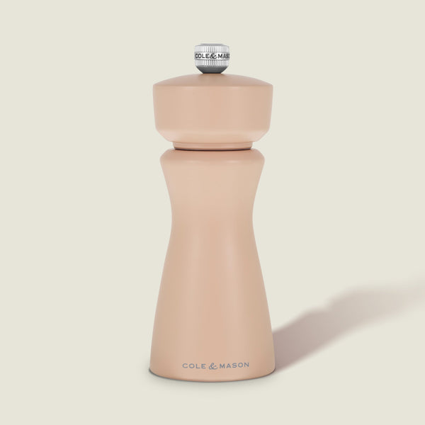 A Cole & Mason Kenton Salt & Pepper Mill in Himalayan Salt, featuring a modern, curved design with a metal knob on top and a durable ceramic grinding mechanism, is set against a plain, light background.