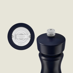 The Kenton Salt & Pepper Mill in Persian Blue Salt by Cole & Mason stands upright next to its detached silver grinding mechanism, with the brand name and “Since 1919” displayed. This stylish mill features a durable ceramic grinder for lasting performance.