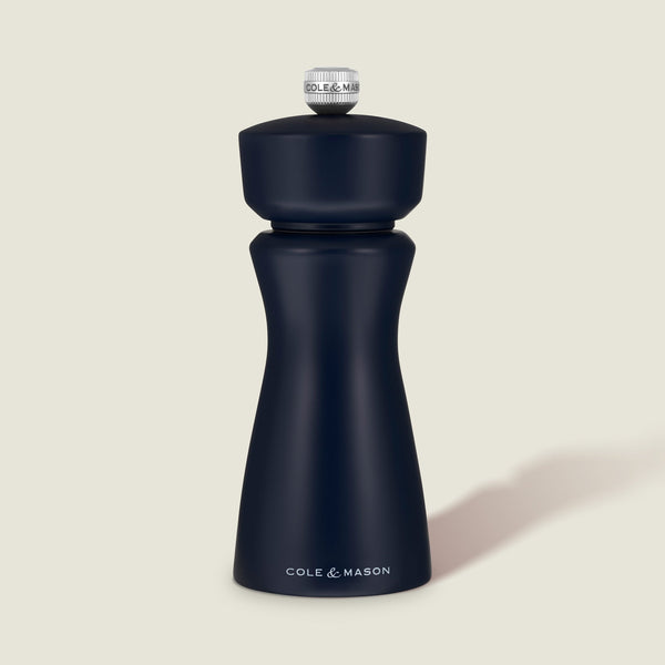 A Persian Blue Cole & Mason Kenton Salt & Pepper Mill, featuring a high-quality ceramic grinder and a sleek design, stands upright on a light beige background, casting a soft shadow to the right.