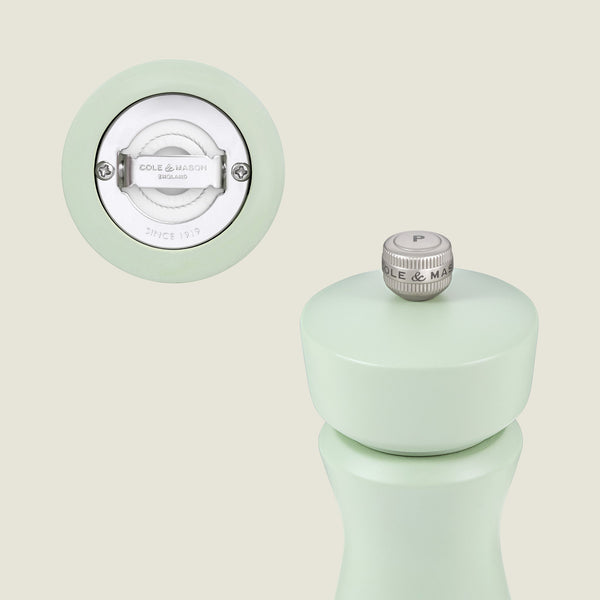 A pastel green Kenton Sage Salt & Pepper Mill by Cole & Mason is shown, highlighting its ceramic mechanism and branded design. The top features a silver, interchangeable knob marked with a P.