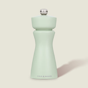 The Cole & Mason Kenton Sage Salt & Pepper Mill features a light green finish, a silver top knob, and a durable ceramic mechanism. It stands upright against a plain, off-white background.