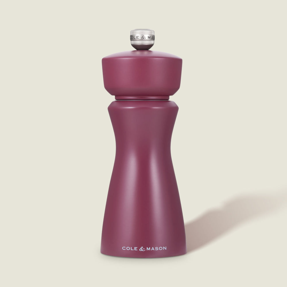 The Cole & Mason Kenton Sichuan Pepper Red Salt & Pepper Mill, with a matte burgundy finish, ceramic mechanism, and silver top knob, stands upright on a plain light background with the brand logo in white near its base.