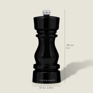 A Cole & Mason London Black Acrylic Pepper Mill (150mm tall, 57mm wide) from the Salt & Pepper Mills collection stands upright on a light background, casting a faint rightward shadow and featuring adjustable grind settings.