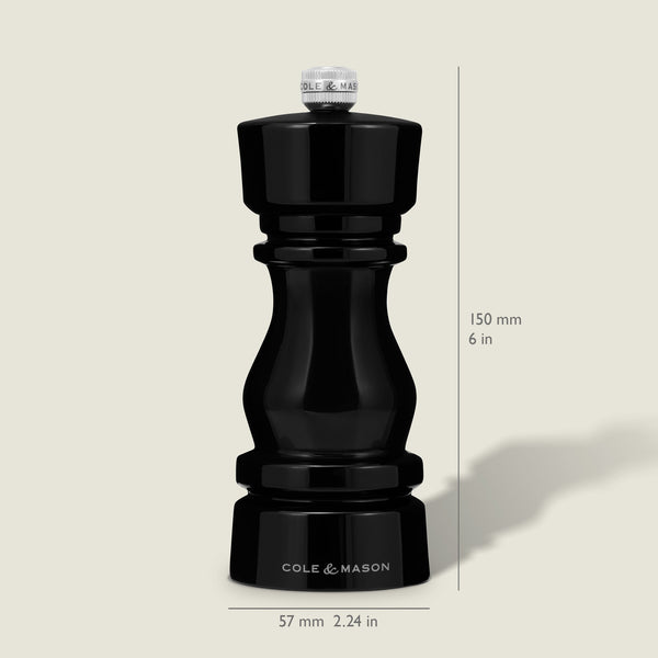 A Cole & Mason London Black Acrylic Pepper Mill (150mm tall, 57mm wide) from the Salt & Pepper Mills collection stands upright on a light background, casting a faint rightward shadow and featuring adjustable grind settings.