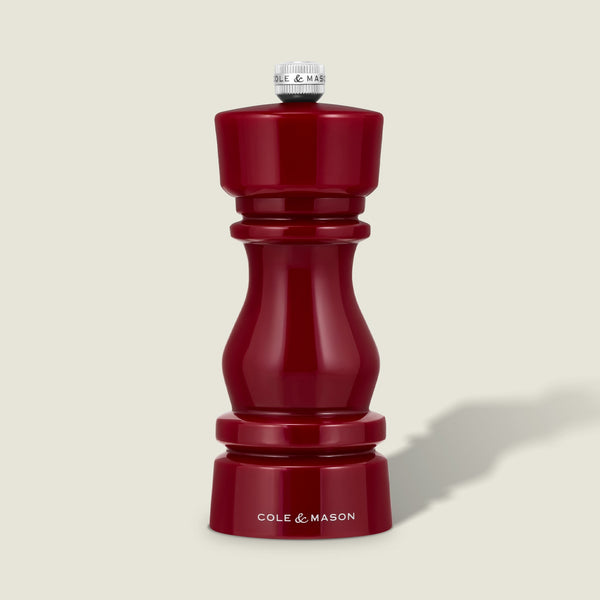 The Cole & Mason London Red Acrylic Salt & Pepper Mill (150mm) features a glossy red finish with a silver knob on top and "Cole & Mason" displayed in white at the base. It comes with an adjustable grinding mechanism for precise seasoning, showcased against a plain light background.