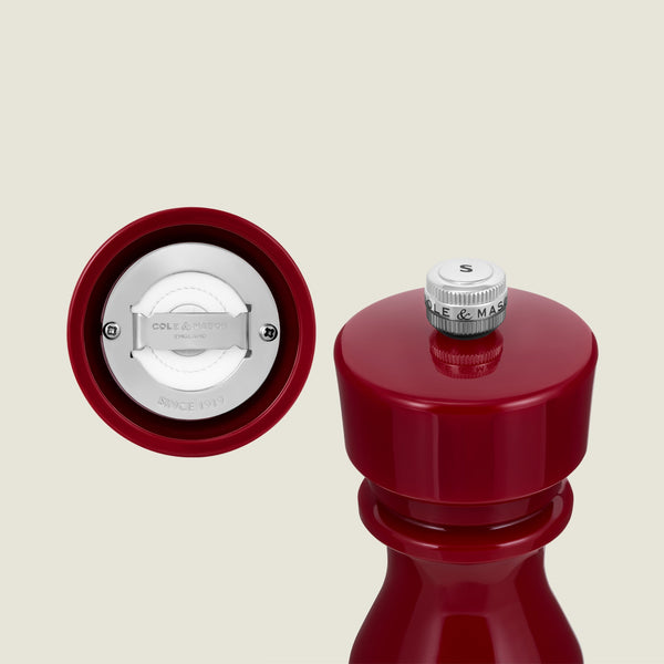 The Cole & Mason London Red Acrylic Salt & Pepper Mill 150mm, from our red salt and pepper mills collection, is shown in a vibrant close-up highlighting its adjustable grinding mechanism and a knob labeled “S” for salt, set against a light background.