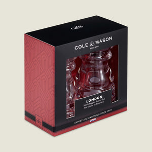 The Cole & Mason London Acrylic Salt Shaker & Pepper Mill Set comes boxed in black and red packaging with white text and geometric patterns, featuring a front window to display the stylish clear acrylic shakers.