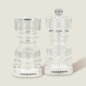 The Cole & Mason London Acrylic Salt Shaker & Pepper Mill Set features two clear grinders with contemporary design details, displayed side by side—ideal for stylish seasoning on any modern table.