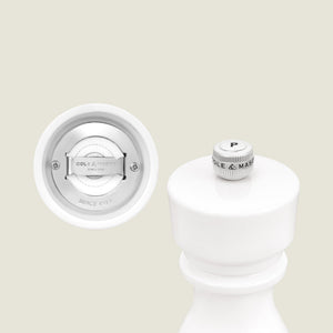 A close-up of the Cole & Mason London White Acrylic Salt & Pepper Mills 150mm highlights the P knob on top and the adjustable grinding mechanism below, set against a plain off-white background.