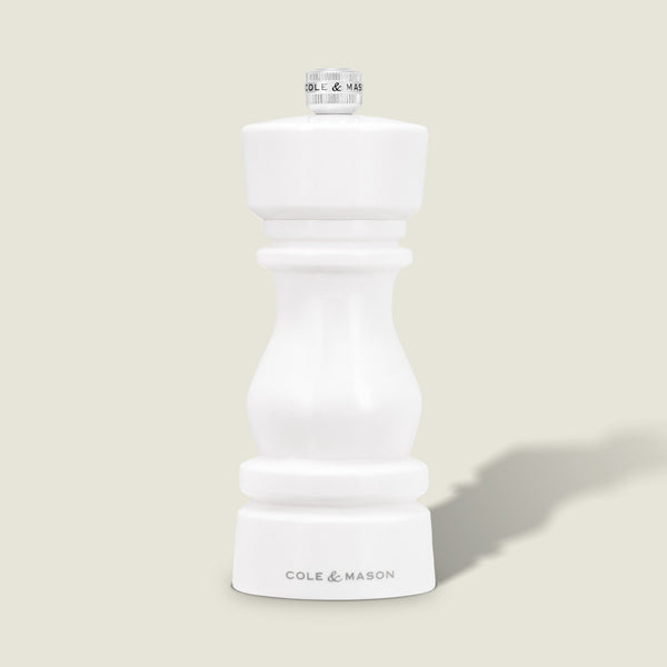 The Cole & Mason London White Acrylic Salt & Pepper Mill (150mm) with adjustable grind stands upright on a light beige background—an elegant, modern addition to any kitchen.