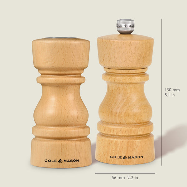 The Cole & Mason London Natural Beech Salt Shaker & Pepper Mill Set, both with grind select technology and branded bases, are shown side by side; the right mill measures 130 mm (5.1 in) tall and 56 mm (2.2 in) wide.