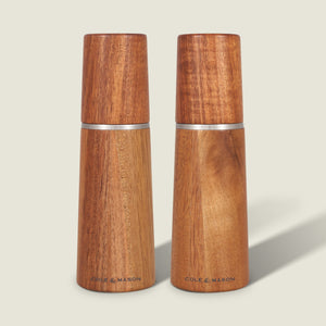 The Cole & Mason UK Marlow Natural Acacia Salt & Pepper Mills feature a smooth, polished finish, silver accents, minimalist design, and an adjustable grinding mechanism for precise seasoning.