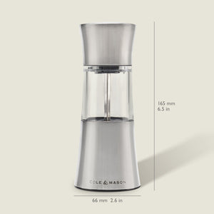 The Cole & Mason Stadhampton Chilli & Spice Mill, made of stainless steel and clear acrylic, stands upright with an ergonomic design, measuring 165 mm high and 66 mm wide. It is shown against a light background.